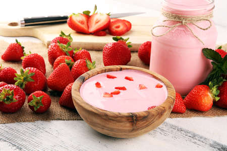 Glass of fresh strawberry yogurt and fresh strawberries on table. Healthy food and drink concept with juicy fruits and dairy fresh dessertの写真素材