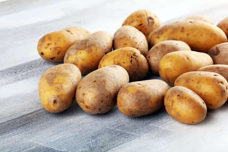 Pile of potatoes lying on wooden boards. Fresh potato on rustic backgroundの写真素材