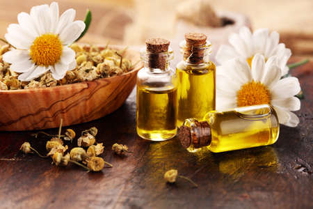Chamomile Composition with essential oil and chamomile flowers on rustic wooden tableの写真素材