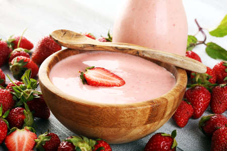 Bowl of fresh strawberry yogurt and fresh strawberries on table. Healthy food and drink concept with juicy fruits and dairy fresh dessertの写真素材