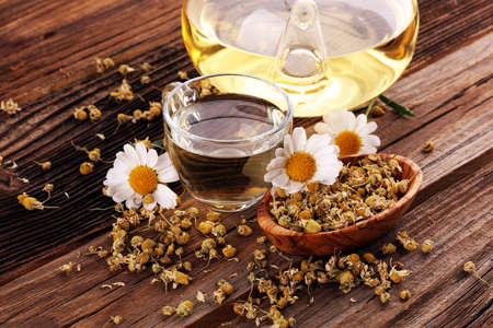 chamomile cup of tea with chamomile flowers on wooden rustic backgroundの写真素材