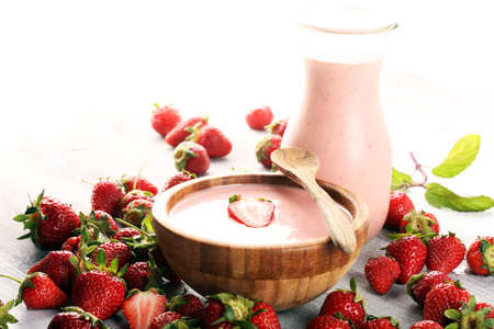 Bowl of fresh strawberry yogurt and fresh strawberries on table. Healthy food and drink concept with juicy fruits and dairy fresh dessertの写真素材