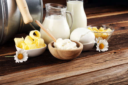 milk products. tasty healthy dairy products on a table on. mozzarella in a bowl, cottage cheese bowl, butter swirls and glass bottle の写真素材