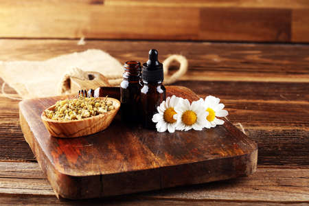 Chamomile Composition with essential oil and chamomile flowers on rustic wooden tableの写真素材