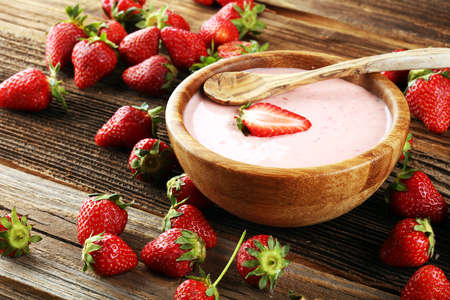 Bowl of fresh strawberry yogurt and fresh strawberries on table. Healthy food and drink concept with juicy fruits and dairy fresh dessertの写真素材