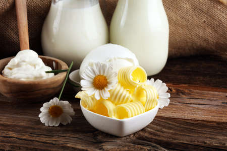 milk products. tasty healthy dairy products on a table on. mozzarella in a bowl, cottage cheese bowl, butter swirls and glass bottle の写真素材