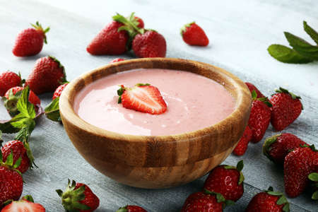 Bowl of fresh strawberry yogurt and fresh strawberries on table. Healthy food and drink concept with juicy fruits and dairy fresh dessertの写真素材