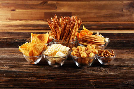 Salty snacks. Pretzels, chips, crackers in glass bowls. Unhealthy products. food bad for figure, skin, heart and teeth. Assortment of fast carbohydrates food. の写真素材