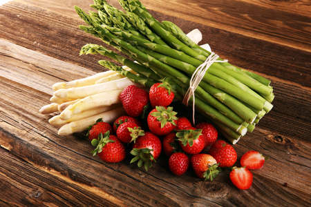 White and green fresh asparagus with a bunch of healthy strawberriesの写真素材