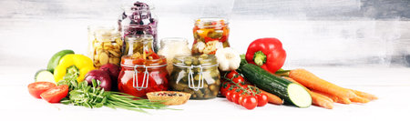 Preserves vegetables in glass jars. Pickled Cucumber, carrot, fermented cabbage and onions on rustic tableの写真素材