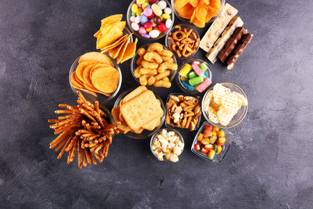 Salty snacks. Pretzels, chips, crackers in glass bowls. Unhealthy products. food bad for figure, skin, heart and teeth. Assortment of fast carbohydrates food. の写真素材