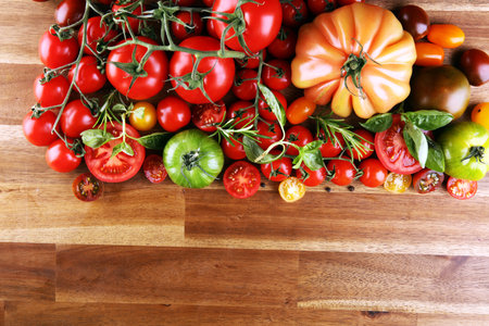 various colorful tomatoes and basil leaves on rustic table. fresh delicious zebra tomato and ccor de...
