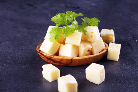 cheese cubes on rusitc table with parsley.