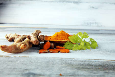 Turmeric powder and fresh turmeric on rustic background.の写真素材