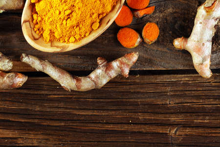 Turmeric powder and fresh turmeric on rustic background.の写真素材