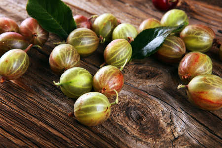 Gooseberries fruits on wooden background. Red and green ripe gooseberries on tableの写真素材