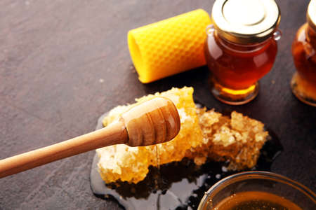 Honey in jar with honey dipper on rustic wooden backgroundの写真素材