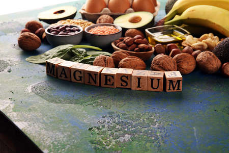 Products containing magnesium: bananas, almonds, avocado, nuts and spinach and eggs on tableの写真素材