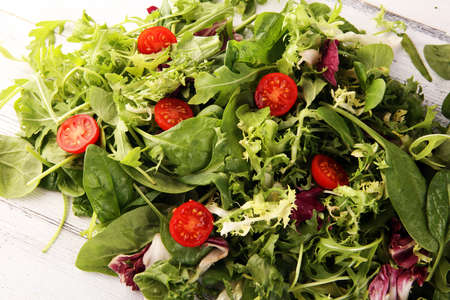 Mix fresh leaves of arugula, lettuce, spinach, beets for salad on rustic backgroundの写真素材