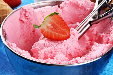 Strawberry ice cream scoop with fresh strawberries and icecream cones on a rustic backgroundの写真素材