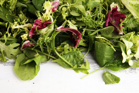 Mix fresh leaves of arugula, lettuce, spinach, beets for salad on rustic background