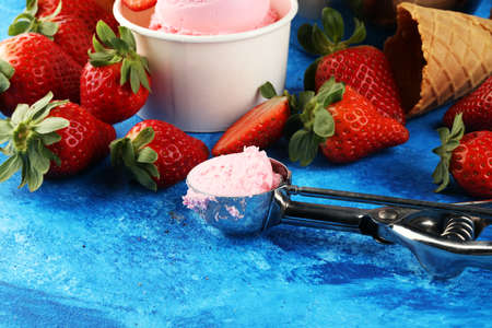 Strawberry ice cream scoop with fresh strawberries and icecream cones on a rustic backgroundの写真素材