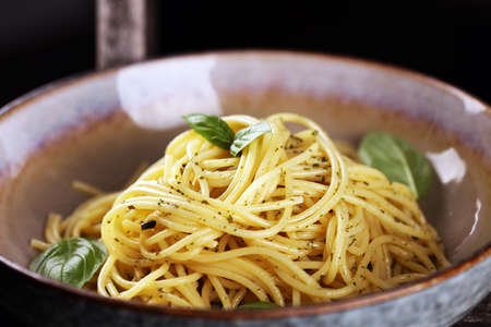 Plate of delicious spaghetti pesto garnished with parmesan cheese and basil on rustic backgroundの写真素材