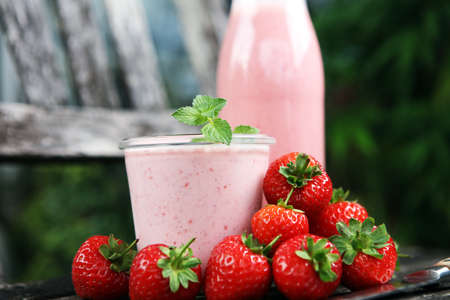 Glass of fresh strawberry shake, smoothie or milkshake and fresh strawberries on table. Healthy food and drink concept with juicy fruitsの写真素材
