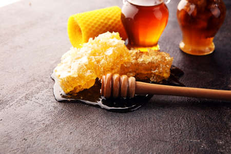 Honey in jar with honey dipper on rustic wooden backgroundの写真素材
