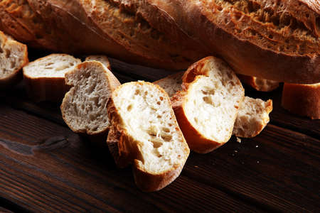 baguette baked bread and sliced baguette on wooden backgroundの写真素材