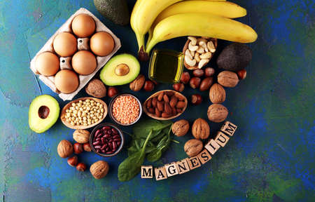 Products containing magnesium: bananas, almonds, avocado, nuts and spinach and eggs on tableの写真素材