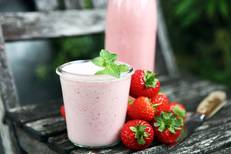Glass of fresh strawberry shake, smoothie or milkshake and fresh strawberries on table. Healthy food and drink concept with juicy fruitsの写真素材