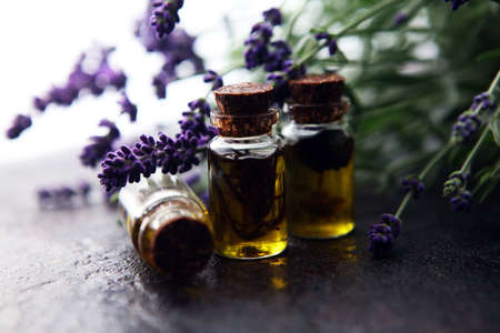 lavender oil in a glass bottle on a background of fresh flowers on tableの写真素材