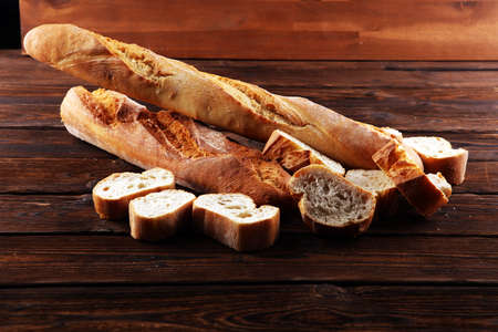 baguette baked bread and sliced baguette on wooden backgroundの写真素材