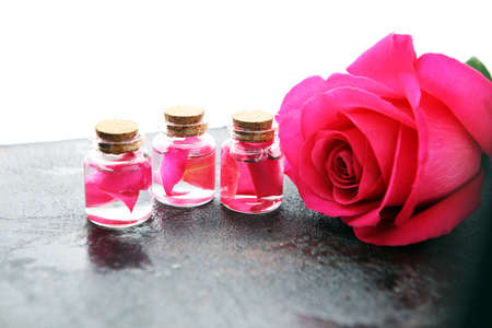 pink rose flower and glass of bottle essential oil. spa and aromatherapy cosmetic concept on backgroundの写真素材