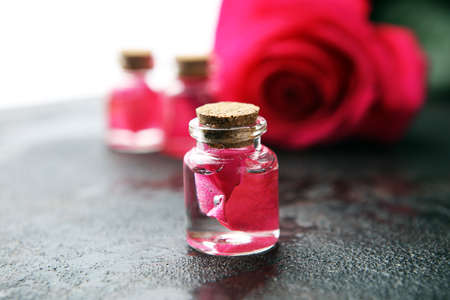 pink rose flower and glass of bottle essential oil. spa and aromatherapy cosmetic concept on backgroundの写真素材