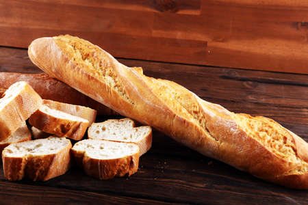 baguette baked bread and sliced baguette on wooden backgroundの写真素材