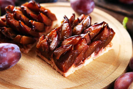 Rustic plum cake on wooden background with plums around. Plum pie conceptの写真素材