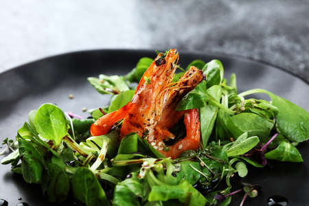 lunch dinner dish meal in a gourmet restaurant with fresh salad food fish elegant gourmet plate. sea seafood shrimp on dark plateの写真素材