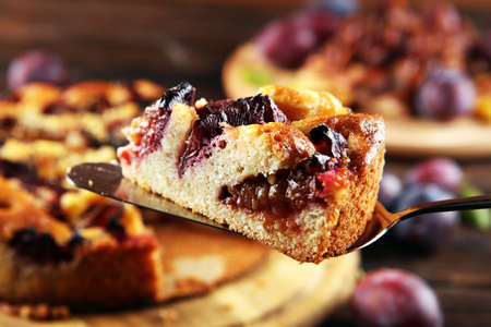 Rustic plum cake on wooden background with plums around. Plum pie conceptの写真素材