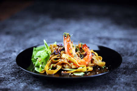 lunch dinner dish meal in a gourmet restaurant. food fish elegant gourmet plate. sea seafood shrimp on dark plateの写真素材
