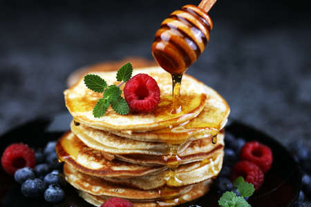 Homemade crepes served with fresh raspberries and powdered sugar on rustic tableの写真素材