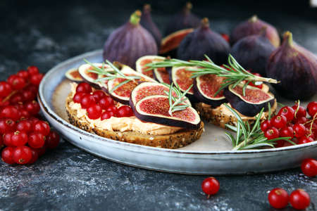 Healthy sweet figs fruit toast with cheese, honey and flower. Fresh fig fruit and flower decoration.の写真素材