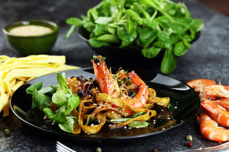 lunch dinner dish meal in a gourmet restaurant. food fish elegant gourmet plate. sea seafood shrimp on dark plateの写真素材
