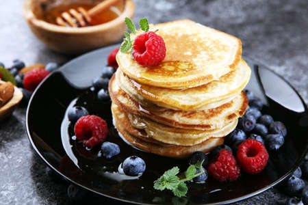 Homemade crepes served with fresh raspberries and powdered sugar on rustic tableの写真素材