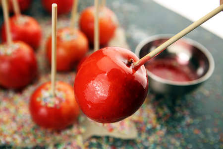 Sweet red glazed toffee candy apples on sticks for sale on farmer market or country fair for kids and parentsの写真素材