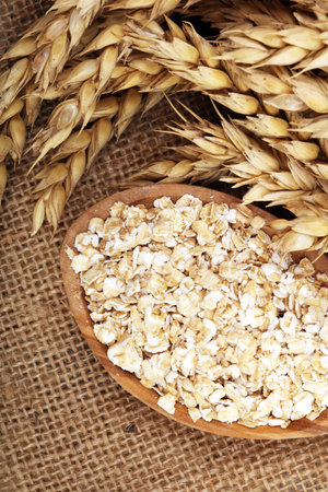 Oat flakes or rolled oats and golden ears of wheat. Healthy lifestyle, healthy eating, vegan diet conceptの写真素材