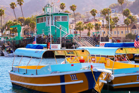 Yellow and blue shore boats site at anchor along the green pier in Avalonのeditorial素材