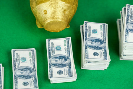 pile of 100 dollar notes with piggy bank on green background