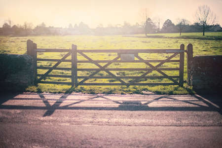 Scenic view of wooden gate on a farm in a rural area of UK countryside under the morning sunlight.の写真素材